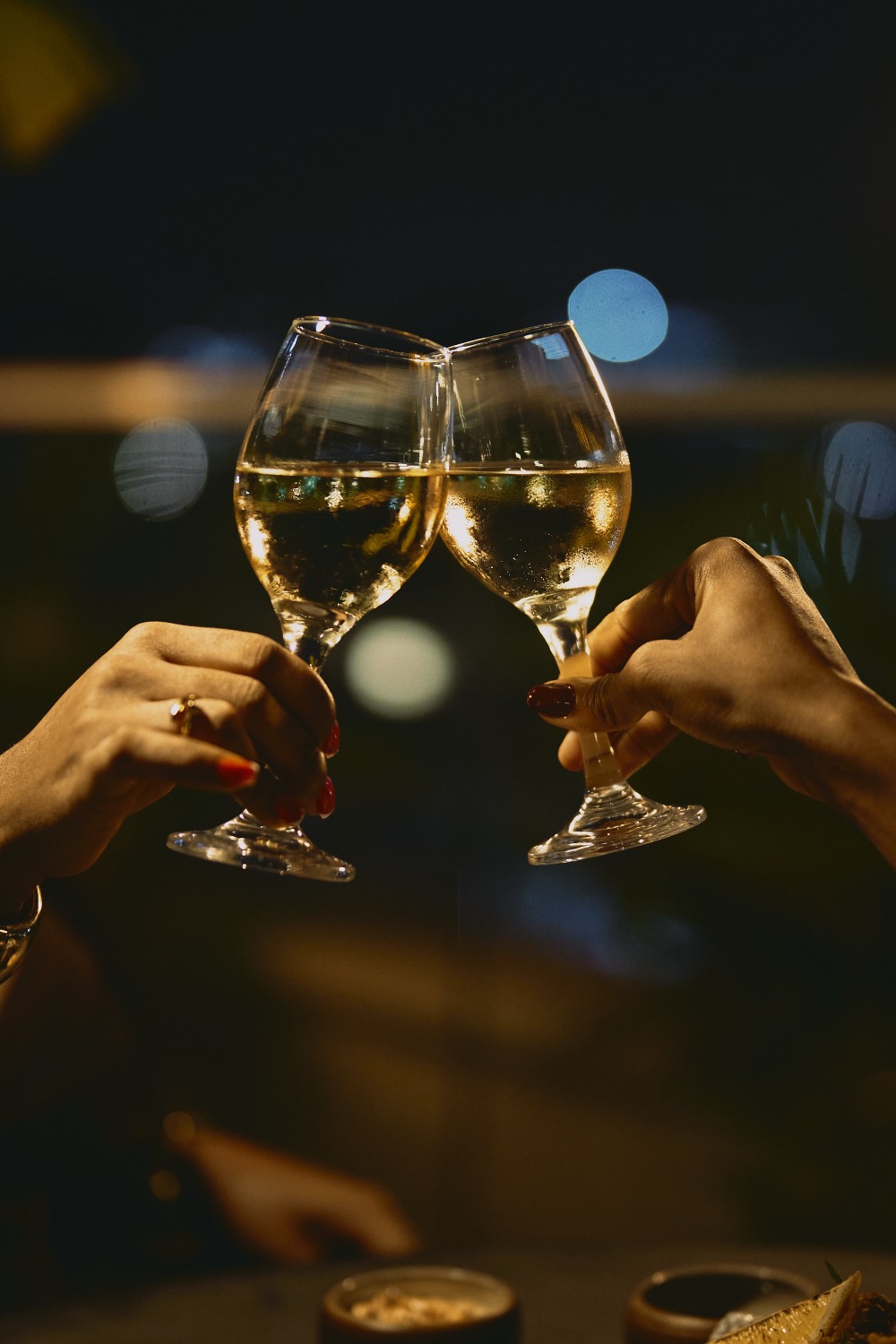 Two glasses of chilled white wine raised in a toast under evening light